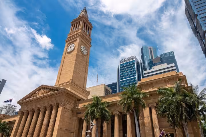 Brisbane City Hall clock tower with neoclassical columns and modern skyscrapers in background