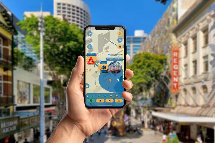 Hand holding smartphone displaying self-guided walking tour map app in Brisbane city street