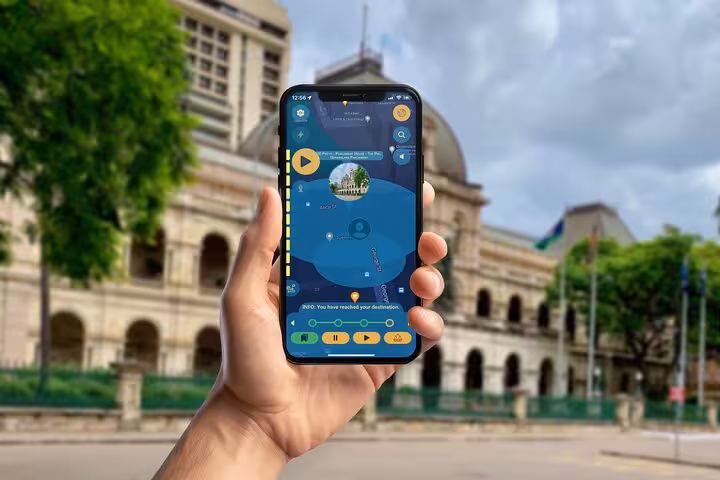 Self-guided Brisbane dark history walking tour app on smartphone in front of iconic Queensland Parliament House