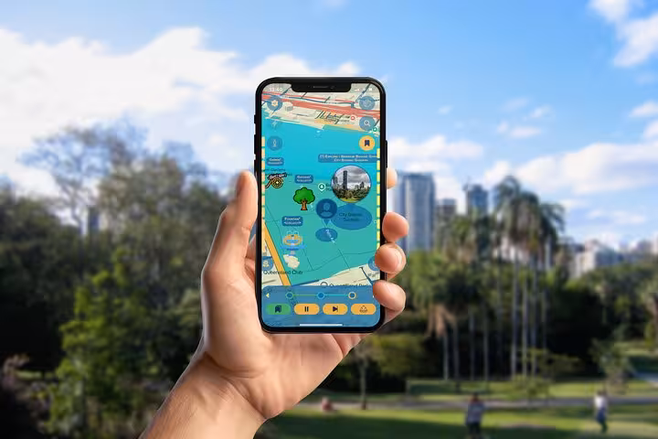 Hand holding smartphone displaying a colorful self-guided walking tour map app in Brisbane park
