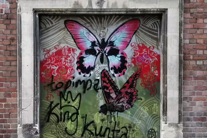 Colorful butterfly street art mural with graffiti on a brick wall in Bristol