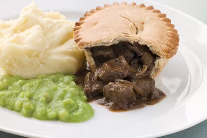 Traditional British steak pie with mashed potatoes and mushy peas, featured on a London food and drinks private tour.