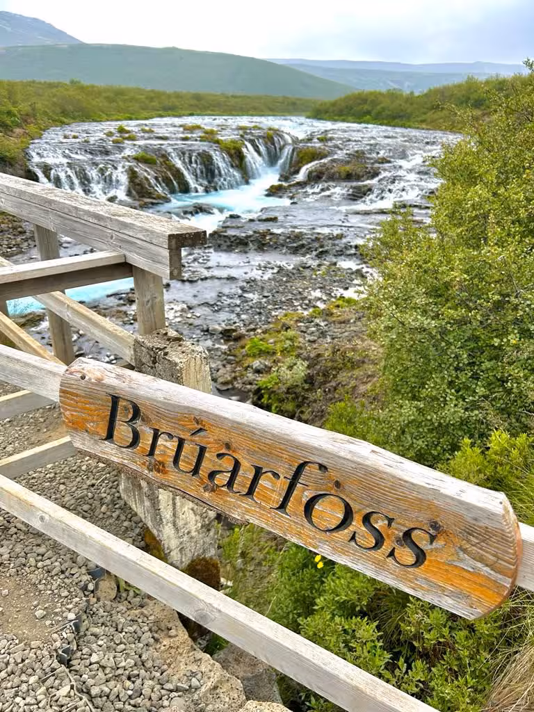 Bruarfoss waterfall wooden sign with stunning turquoise cascades on Iceland private Golden Circle full-day tour.