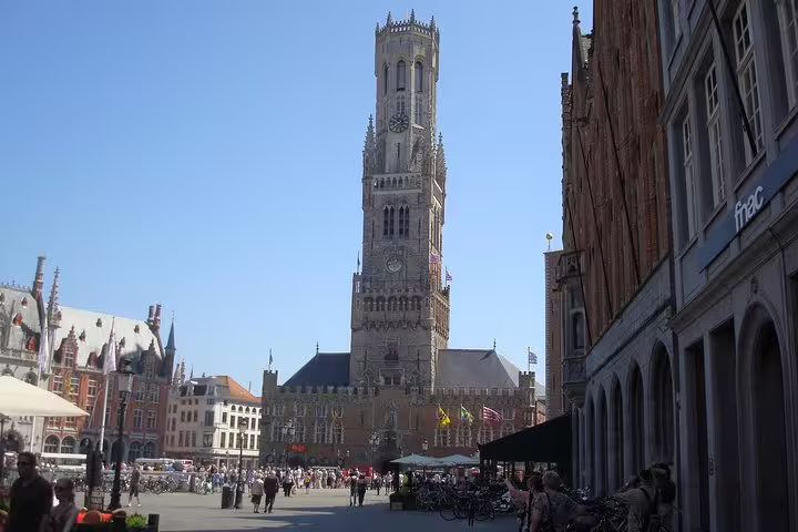 View of the iconic Belfry of Bruges in a bustling square, perfect for a private day trip from Brussels to Bruges.