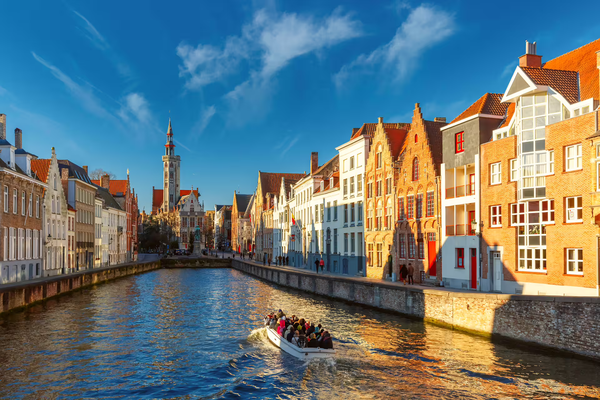 Boat on Bruges canal with historic façades, highlight of Bruges in 1 day walking tour audioguide