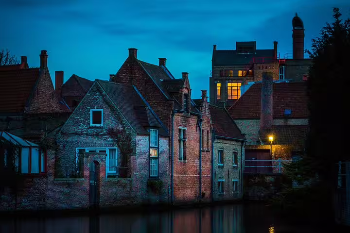 Scenic evening view of historic brick buildings along a tranquil canal in Bruges, ideal for a private day trip from Brussels.