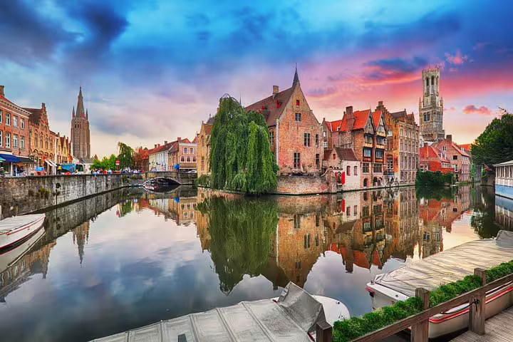 Scenic Bruges canal at sunset with medieval buildings and Belfry, on a guided day tour from Paris with hotel pick-up