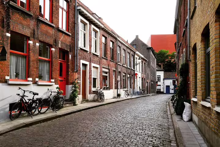 Charming cobblestone street in Bruges with traditional brick houses and bicycles, perfect for a private day trip from Brussels.