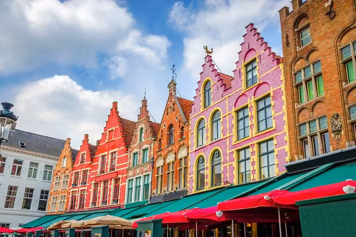 Colorful stepped-gable facades and green cafe awnings at Bruges Market Square