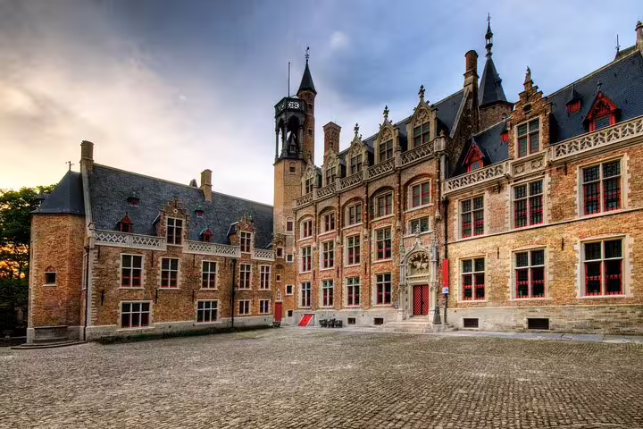 Historic medieval courtyard of Bruges with Gothic brick architecture and cobblestone square at dusk