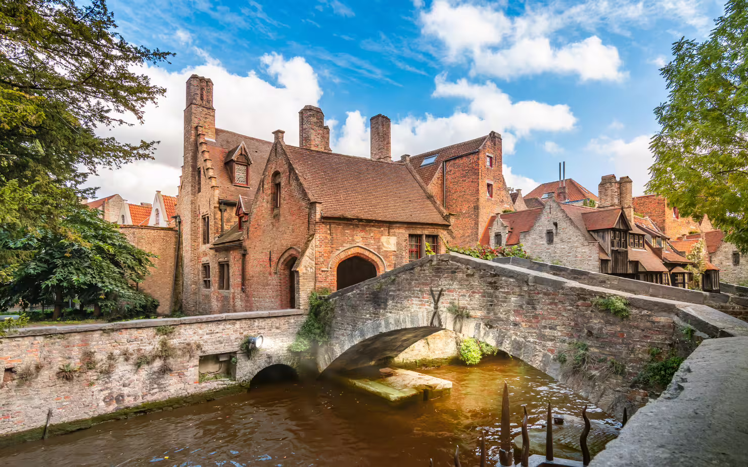 Medieval canal bridge and brick houses in Bruges, Belgium, ideal stop on a 1-day walking tour audioguide