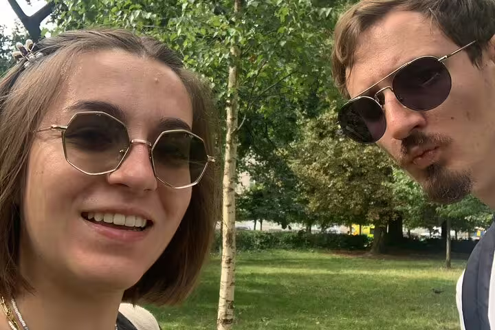 Two smiling friends wearing sunglasses enjoying a sunny day in a Brussels park