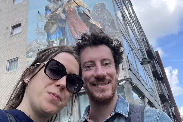 Couple taking selfie in front of large comic strip mural on Brussels building