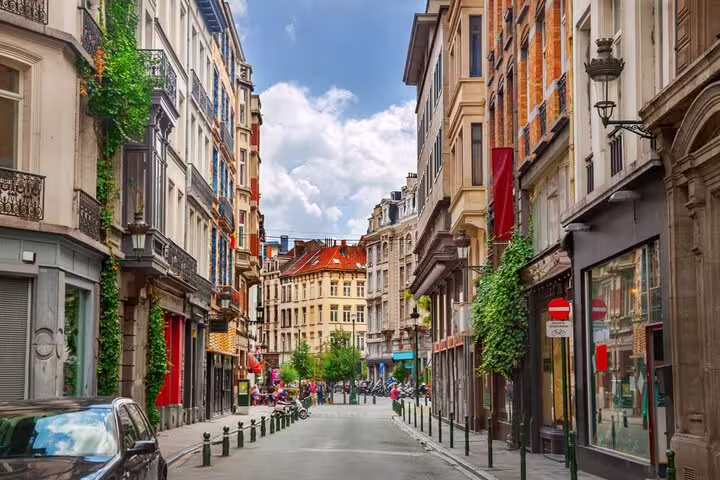 Charming Brussels street lined with ivy-covered buildings, shops, and classic European architecture on a sunny day