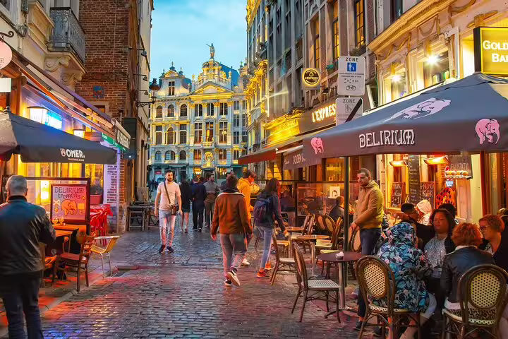 Evening scene in Brussels' vibrant street with outdoor cafes and historic architecture, perfect for a private tour with beer tasting.