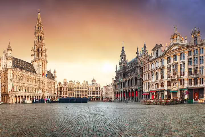 Grand Place Brussels at sunrise with ornate Gothic Town Hall and gilded guild houses surrounding cobblestone square