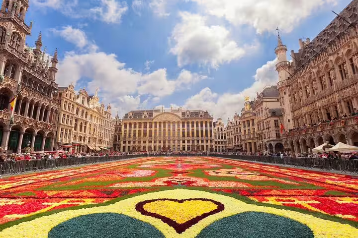 Grand Place Brussels flower carpet with ornate Gothic guild houses and blue sky backdrop