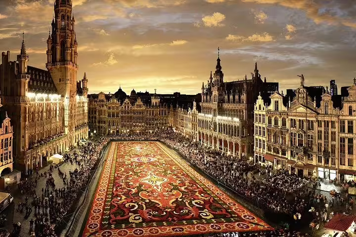 Grand Place Brussels illuminated at dusk with famous flower carpet and Gothic Town Hall tower
