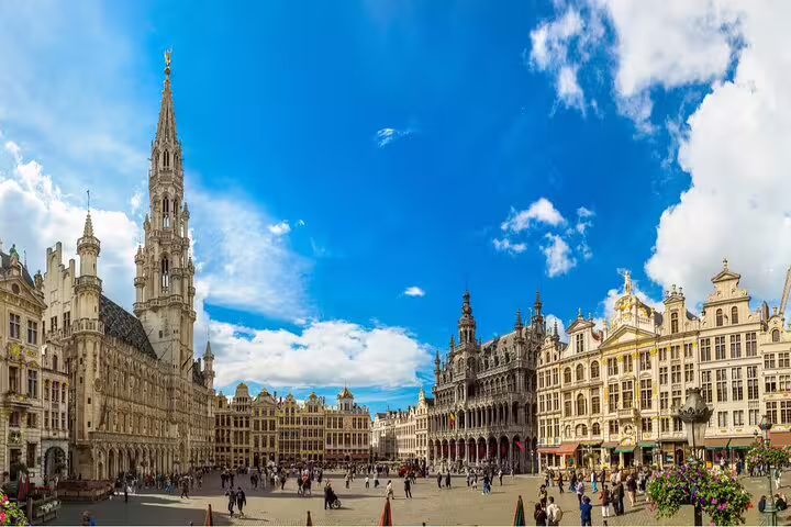 Grand Place square in Brussels Old Town with ornate guild houses and tall Town Hall spire on sunny day