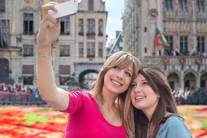 Two women taking a selfie in Brussels' vibrant Grand Place during a private tour with a beer stop, capturing the city's charm.