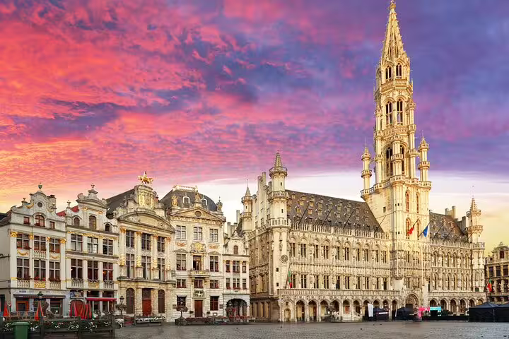 Grand Place Brussels with Gothic Town Hall and ornate guild houses under a vibrant sunset sky