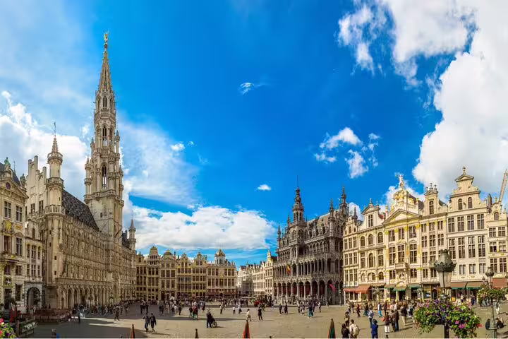 Grand Place Brussels historic square with Gothic Town Hall and ornate guild houses under blue sky
