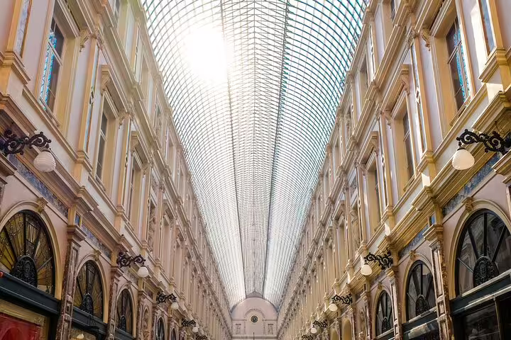 Elegant glass-roofed gallery arcade in Brussels with ornate neoclassical architecture and arched storefronts