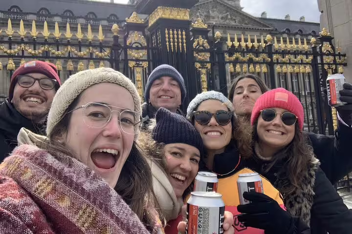 Group of friends holding beer cans on Brussels self-guided walking tour in front of ornate golden gate