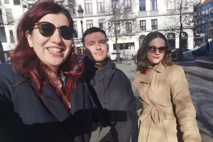 Three tourists taking a selfie on a sunny Brussels street during a self-guided walking tour