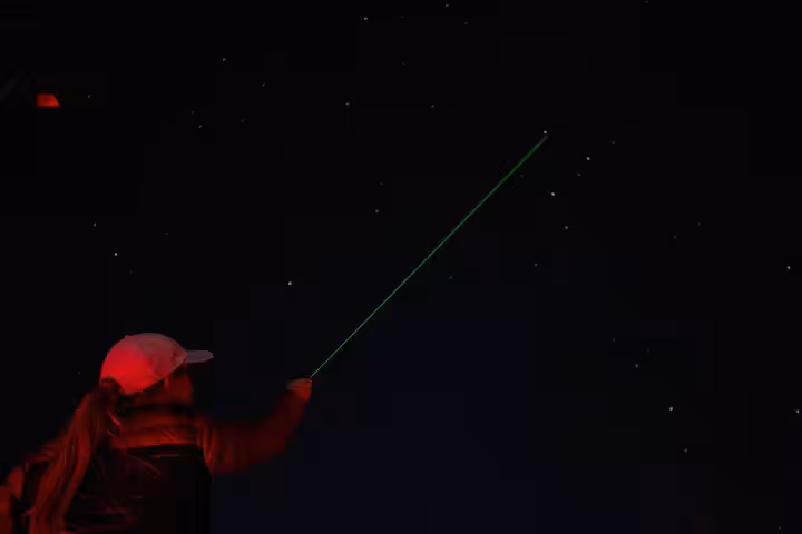 Ranger points green laser at constellations on a Bryce Canyon stargazing tour under dark night skies