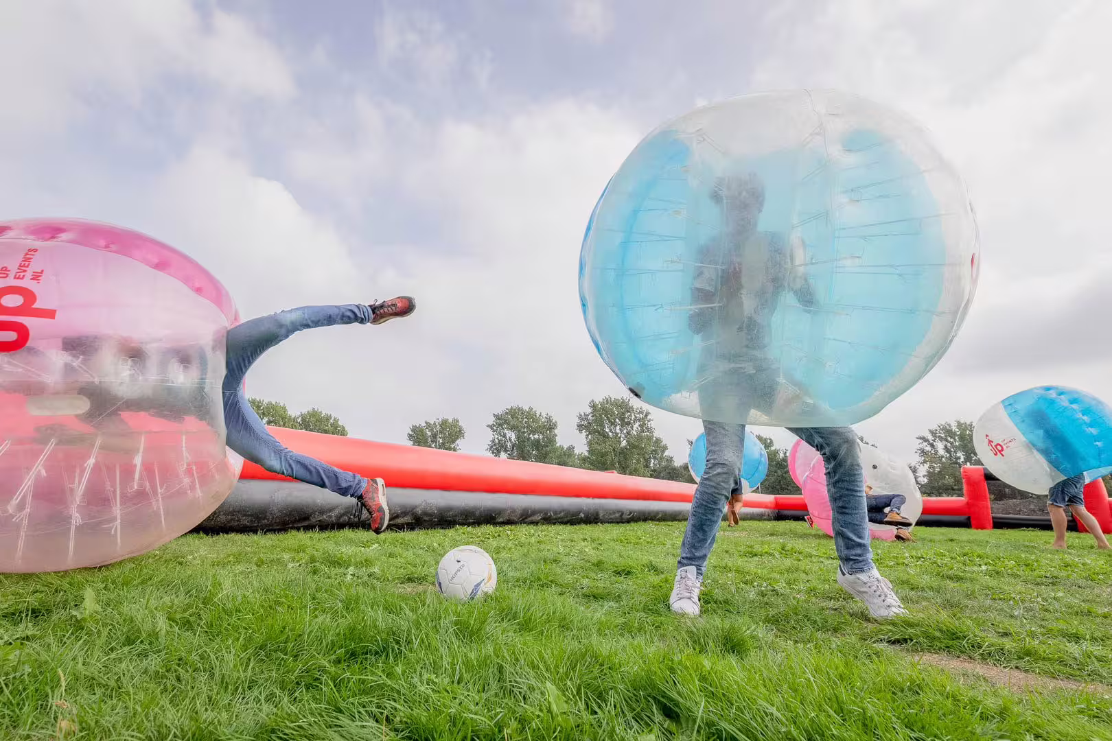 Friends collide in bubble suits on grass pitch during bubble football match in Weesp near Amsterdam