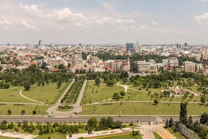 Aerial view of Bucharest city park with green lawns, pathways, and urban skyline in background