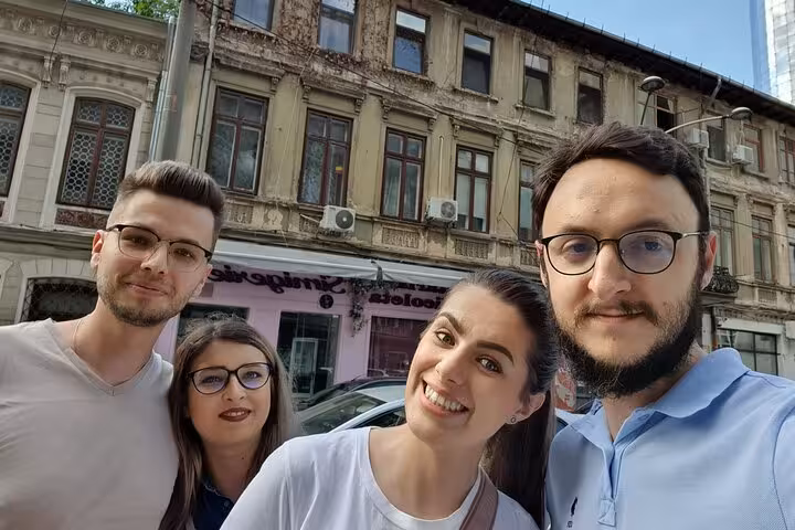 Four young adults smiling together on a Bucharest street with historic communist-era buildings in background