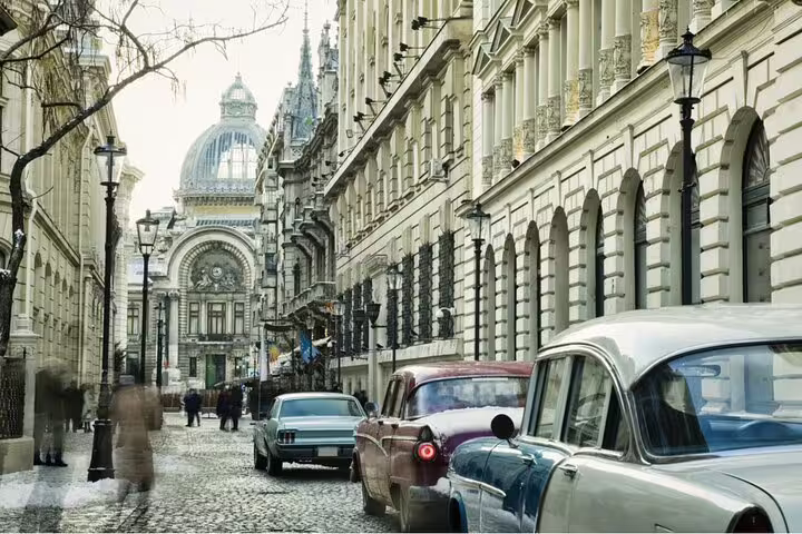 Historic cobblestone street in Bucharest with classic cars and ornate communist-era buildings