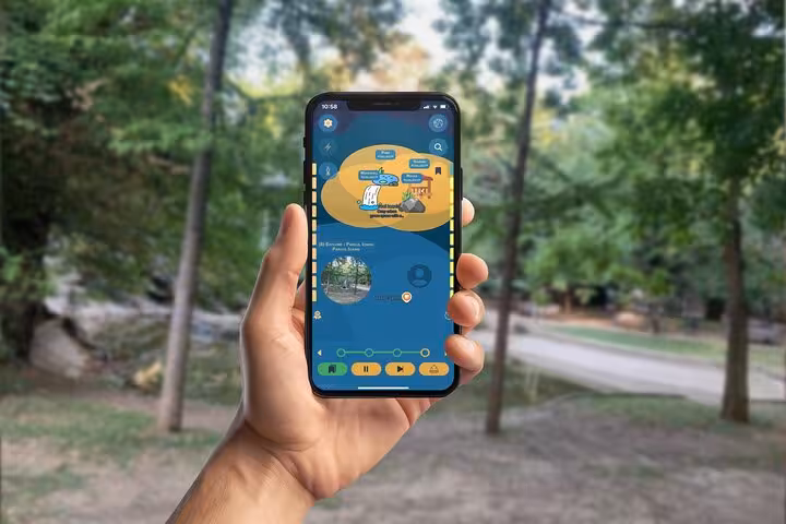 Hand holding smartphone with interactive walking tour mobile app in a green park setting