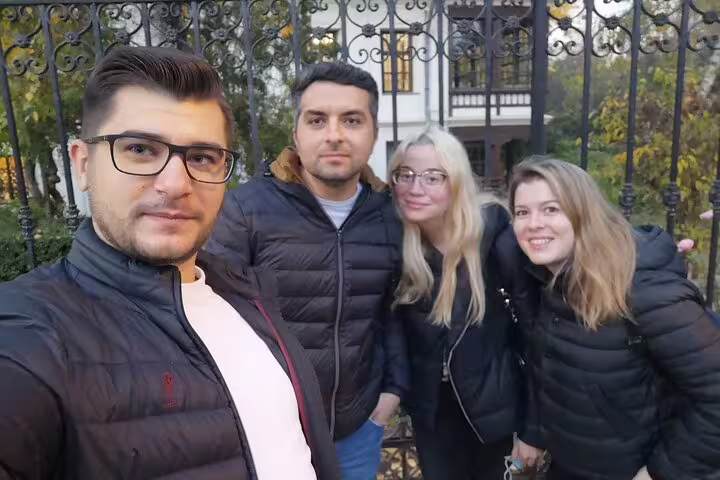 Four friends posing for a selfie in front of ornate iron gates in Bucharest Old Town