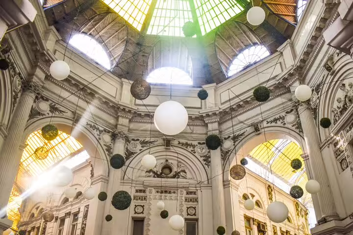 Ornate domed interior of Bucharest Old Town building with hanging white and green spherical decorations