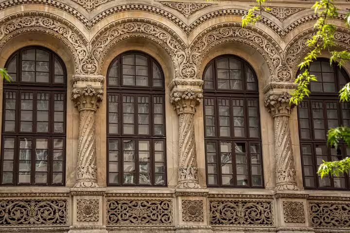 Ornate neo-gothic stone facade with arched windows and decorative columns in Bucharest