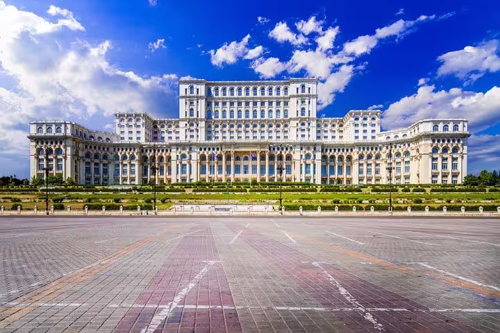 Majestic front view of Bucharest's Palace of Parliament under a vibrant blue sky, perfect for Italian guided tours.
