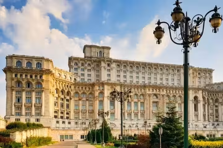 Elegant side view of the Palace of Parliament in Bucharest with classic street lamps, featured in Italian tours.