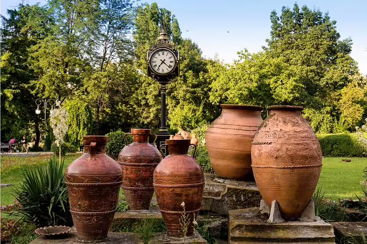 Large decorative terracotta clay pots and ornate street clock in a Bucharest park garden