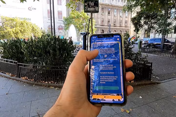 Traveler using a self-guided tour app at Piata 21 Decembrie 1989 sign in Bucharest Revolution walking tour