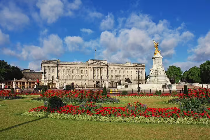 Buckingham Palace with vibrant gardens under a blue sky, perfect for exploring on a London layover tour.