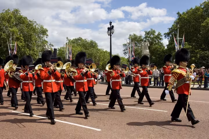 Illustrated Buckingham Palace with two Royal Guards in red uniforms standing at ornate gates