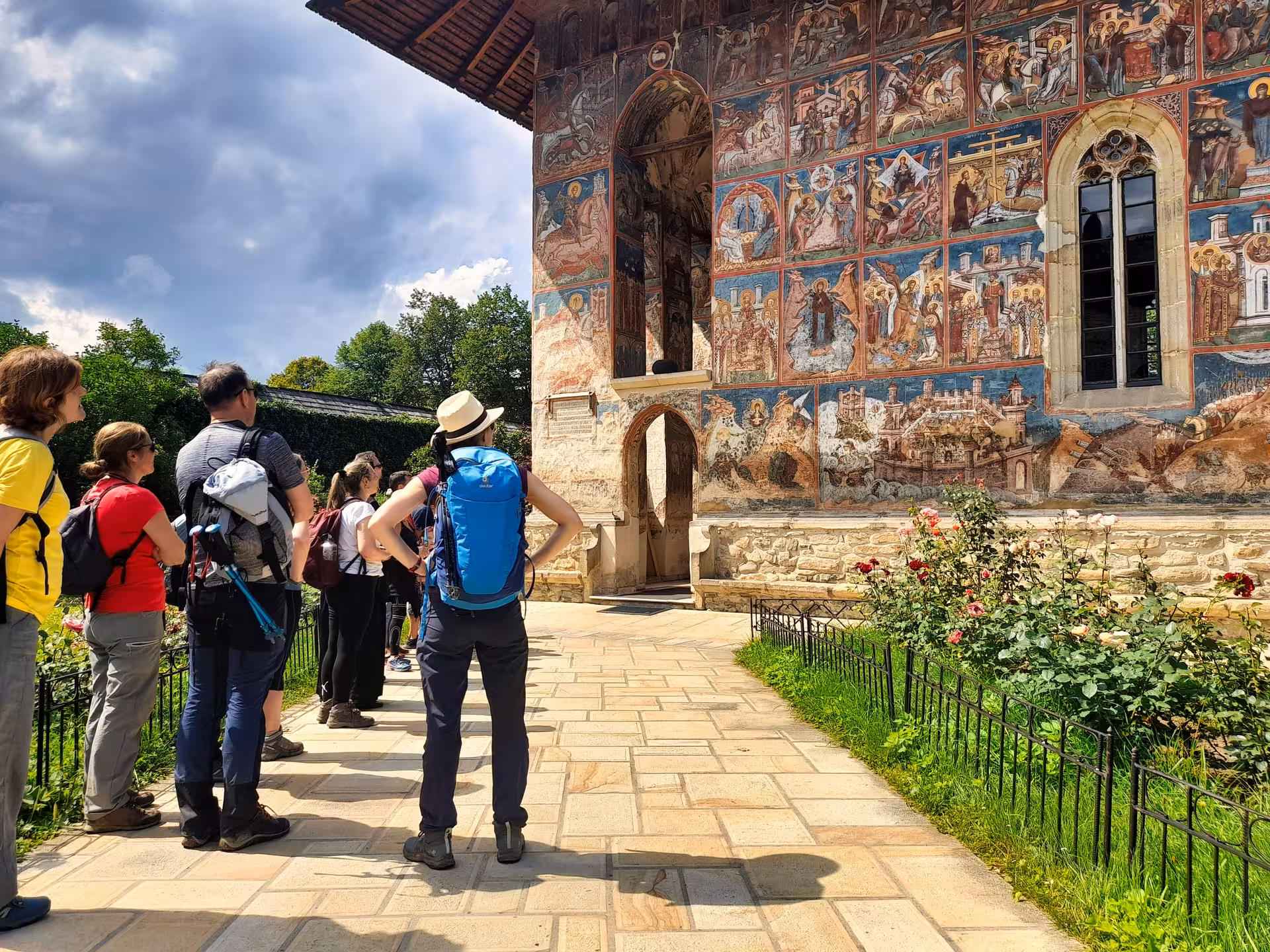 Tour group admiring vivid exterior frescoes at a Bucovina painted monastery on a 2-day guided Romania trip