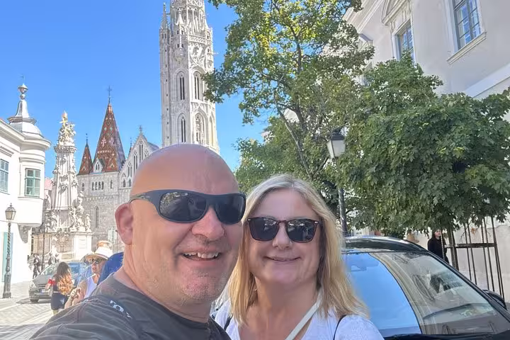 Couple smiling in selfie with Matthias Church and Buda Castle District in Budapest background