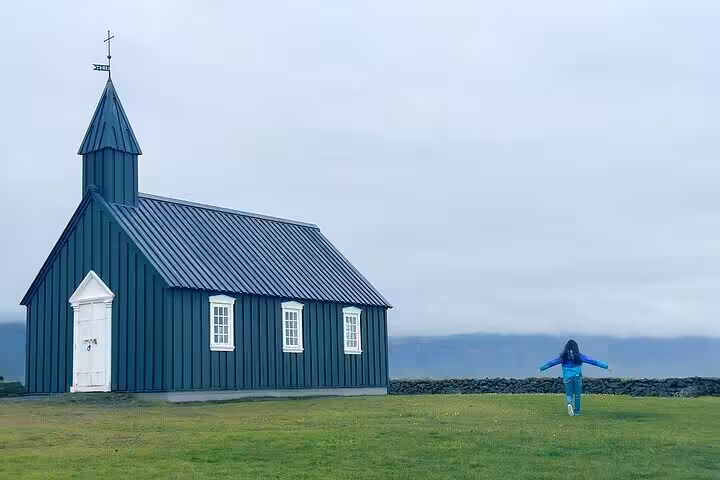 Person jumping near the iconic black Búðakirkja church on Snæfellsnes Peninsula, Iceland