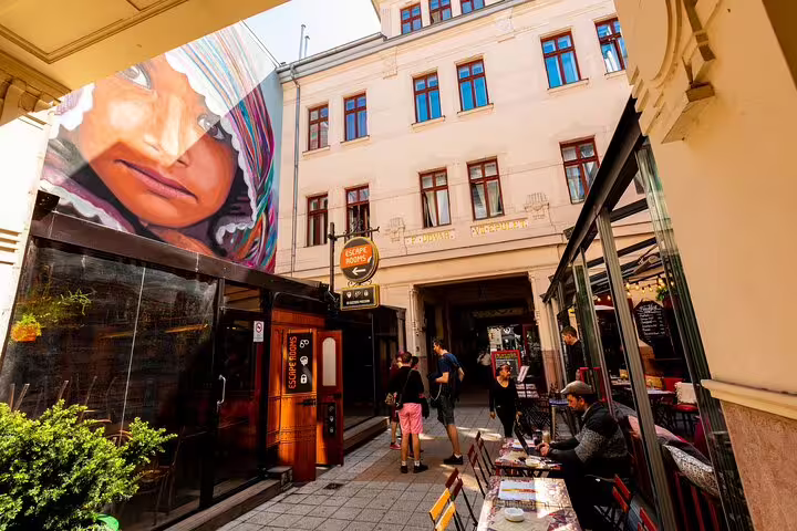 Budapest Jewish Quarter courtyard with escape rooms sign, street art mural, and outdoor café seating