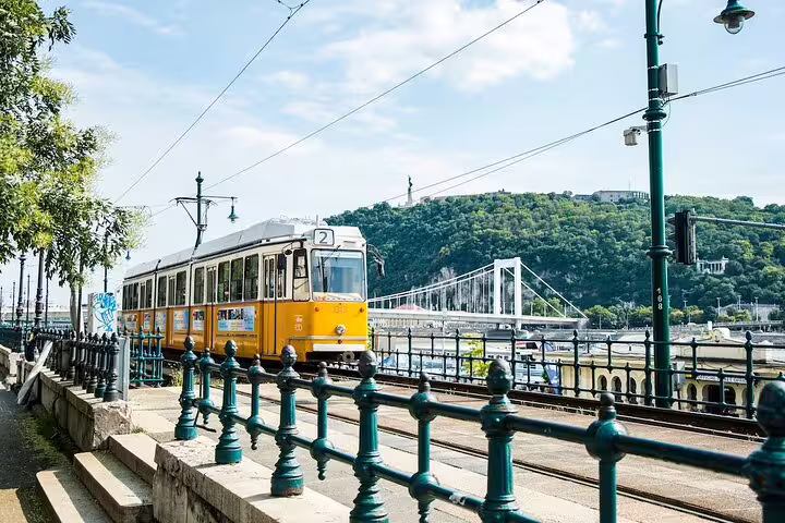 Yellow tram number 2 along the Danube riverbank in Budapest with Gellért Hill in background