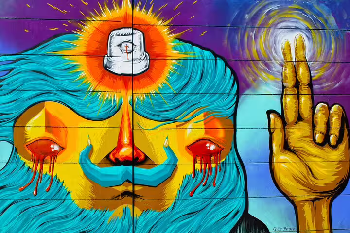 Colorful mural of crying face and raised hand, a highlight on the Budapest street art walking tour